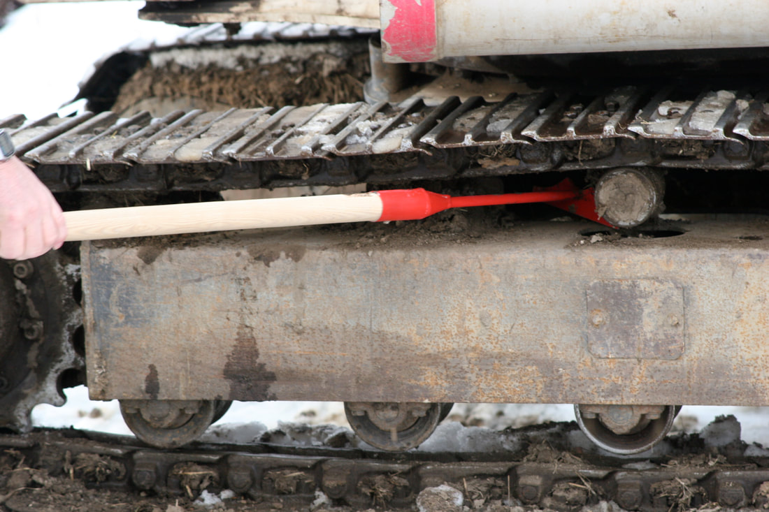 Cleaning heavy equipment undercarriage using Track Hoe tool